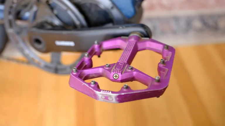 A purple Crankbrothers Stamp 7 pedal mounted on a right crank arm of a bicycle.