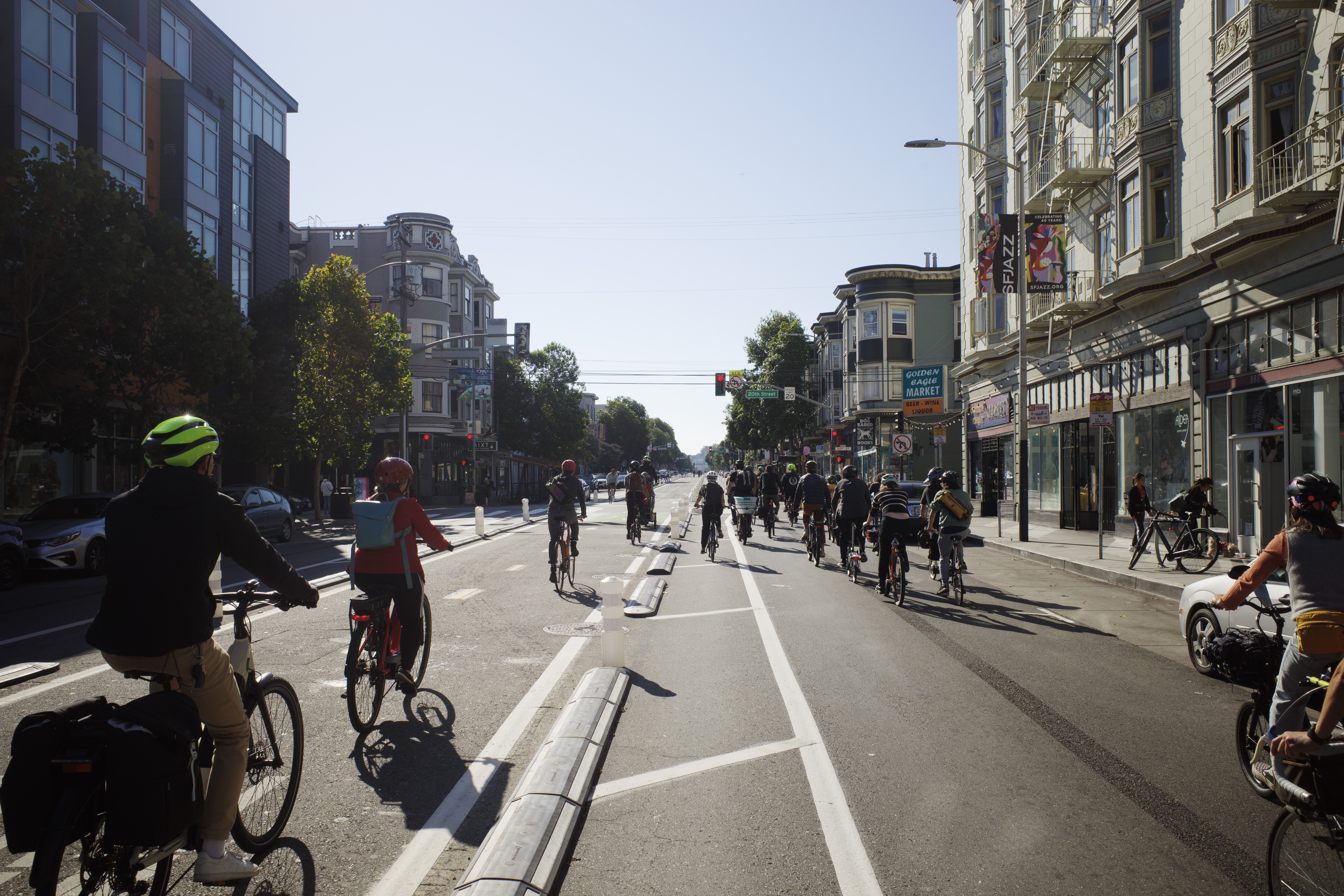 A group of a few dozen bicyclists taking a traffic lane and center running bike lane with residences on both sides.
