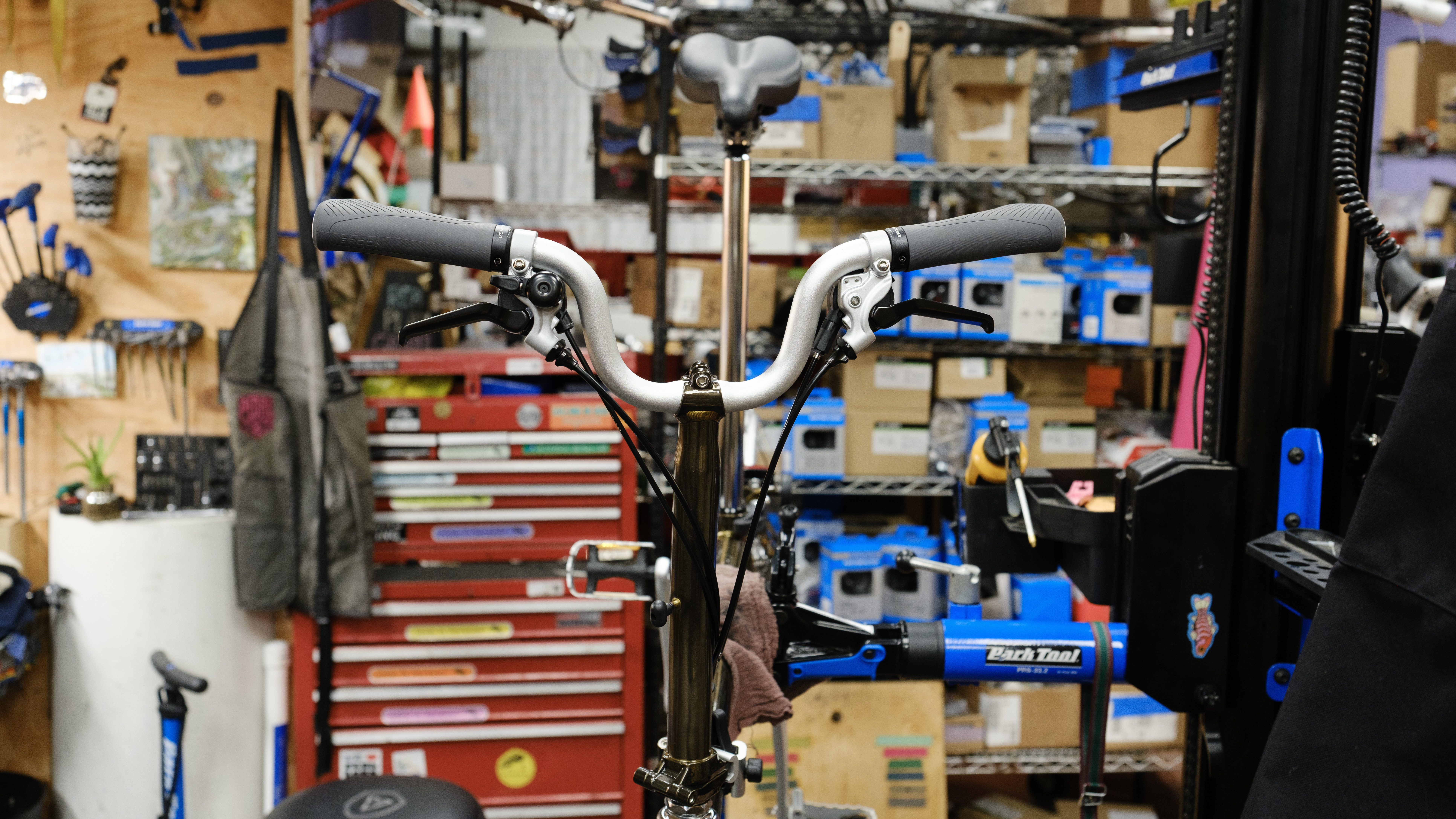 The front of a Brompton in a bike stand highlighting the handlebars with new grey Ergon grips.