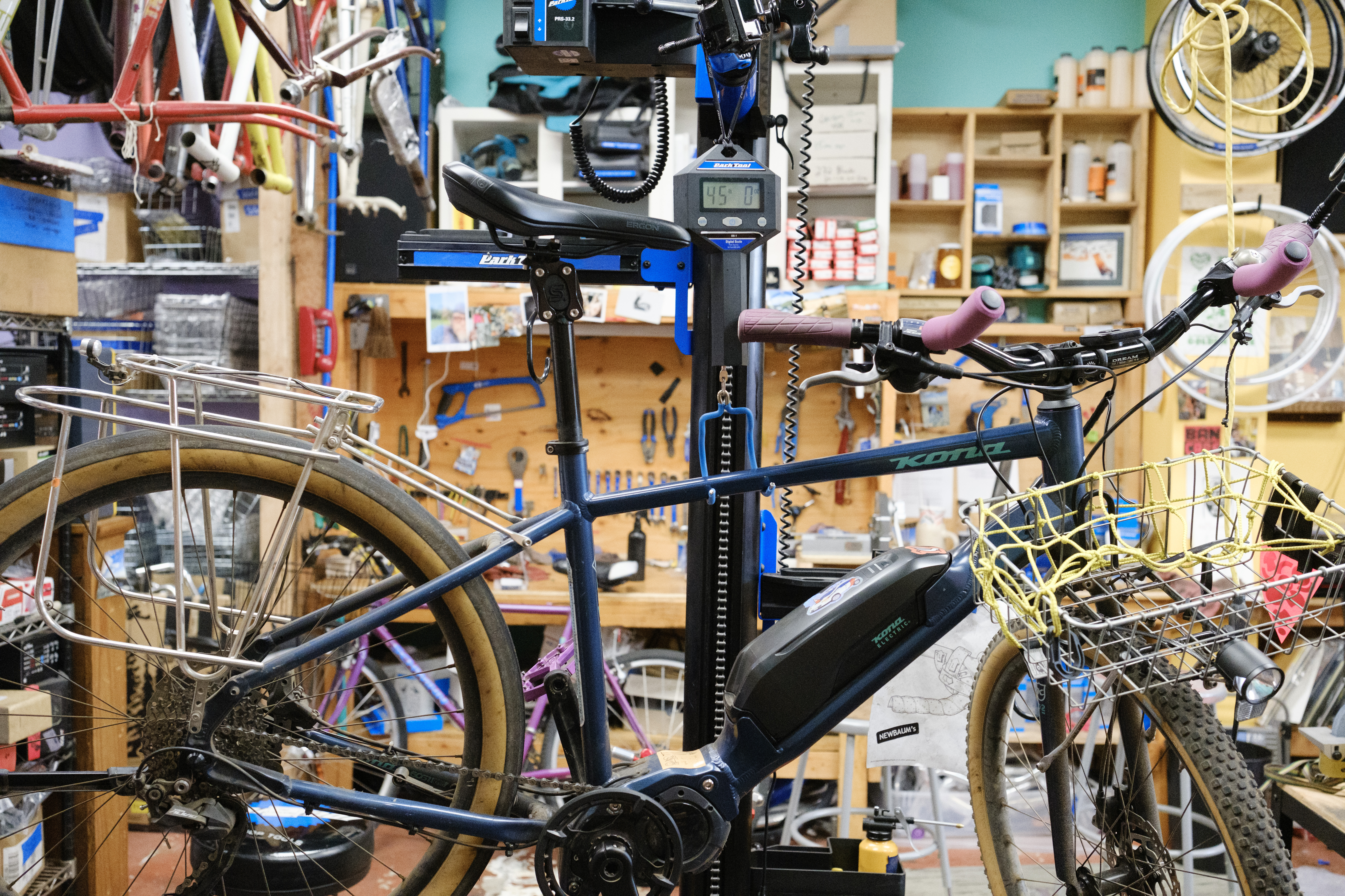 A blue bike on a hanging scale reading out 45 lbs 0 oz