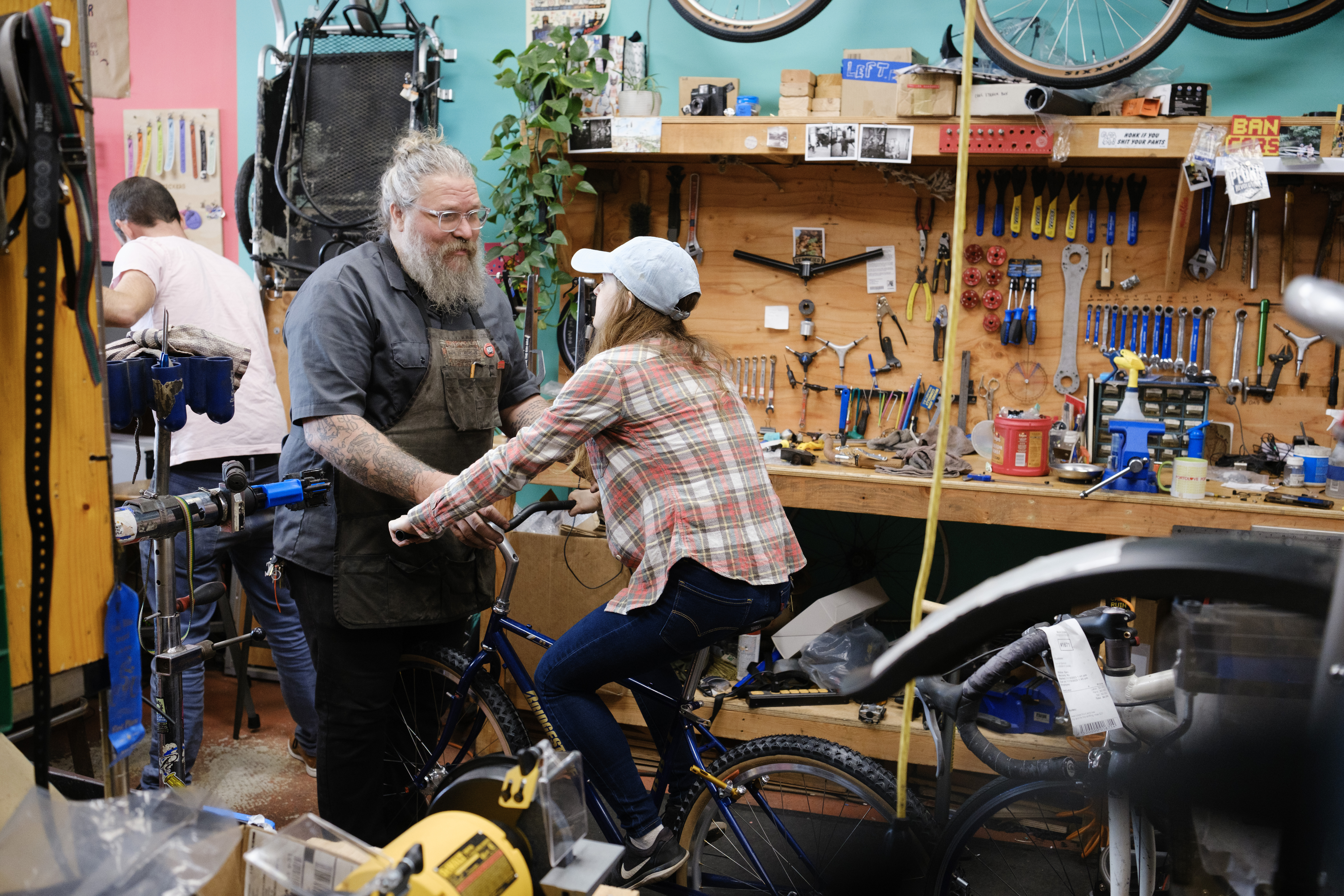Kat sitting on her bike with her feet resting on the downtube while Jay holds the bars and bike upright.