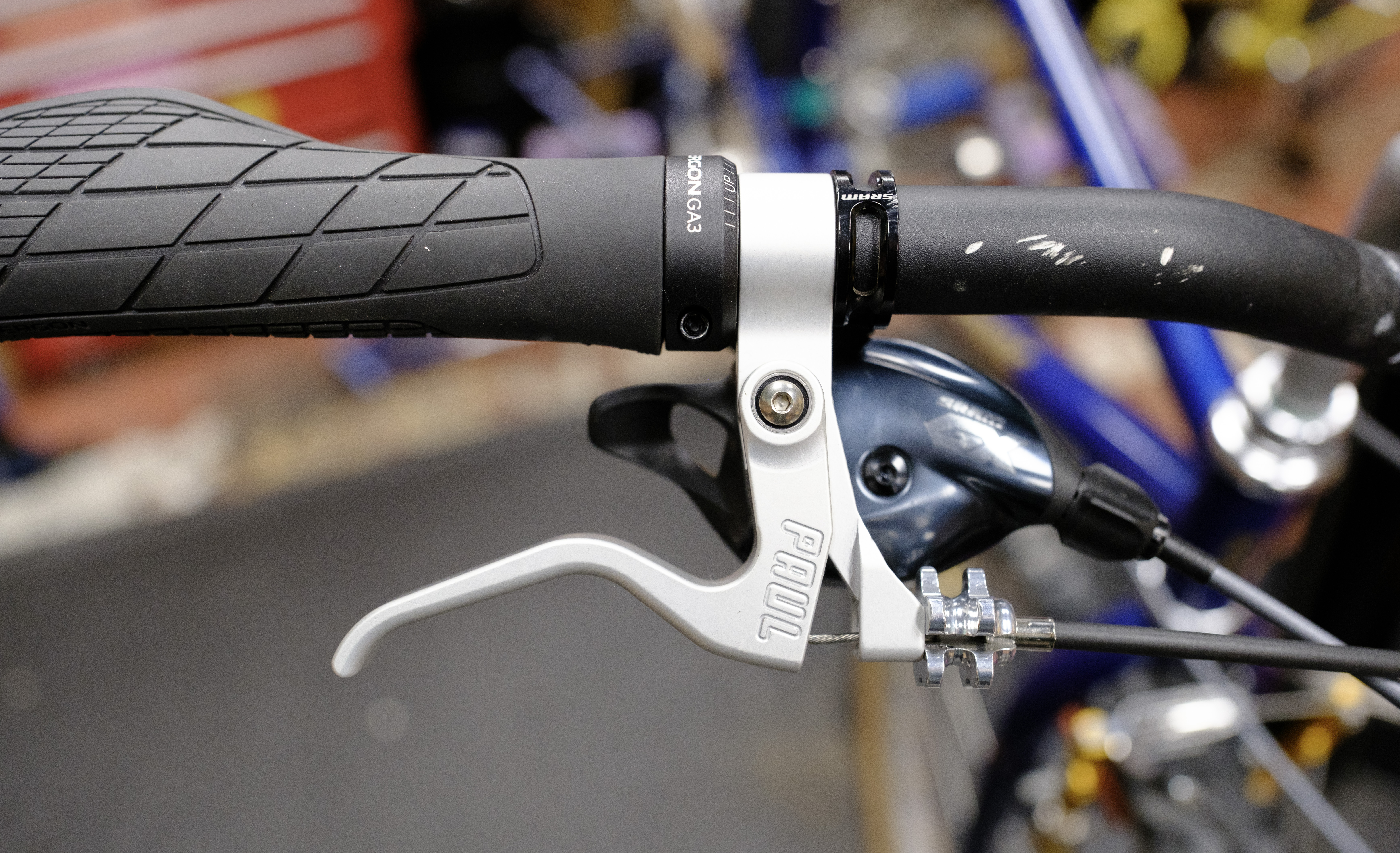 The right side of a bike cockpit. There's a black Ergon grip, silver PAUL lever, and black SRAM shifter.