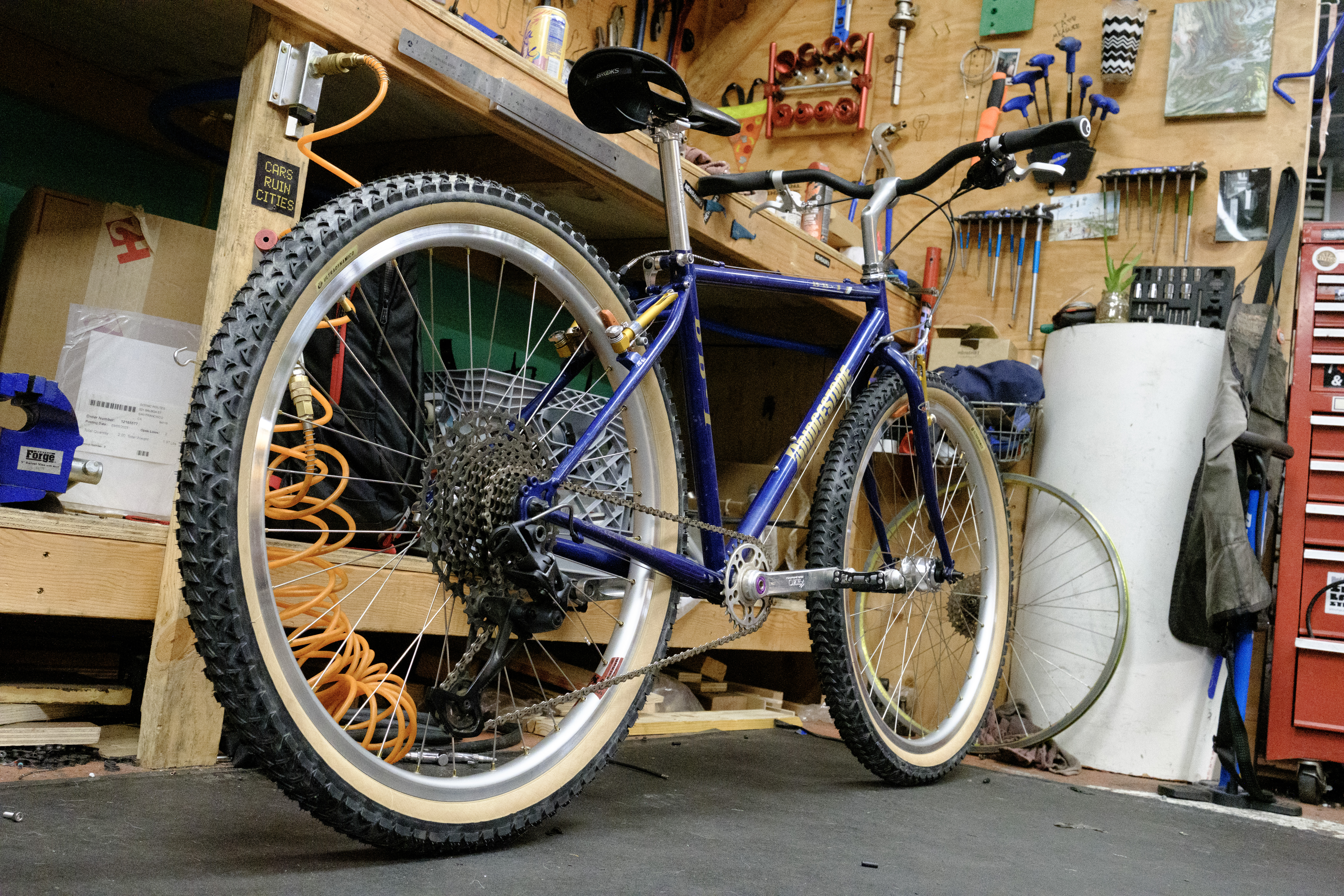 The completed bike with a 'Cars Ruin Cities' sticker on the bench the bike is leaning on.