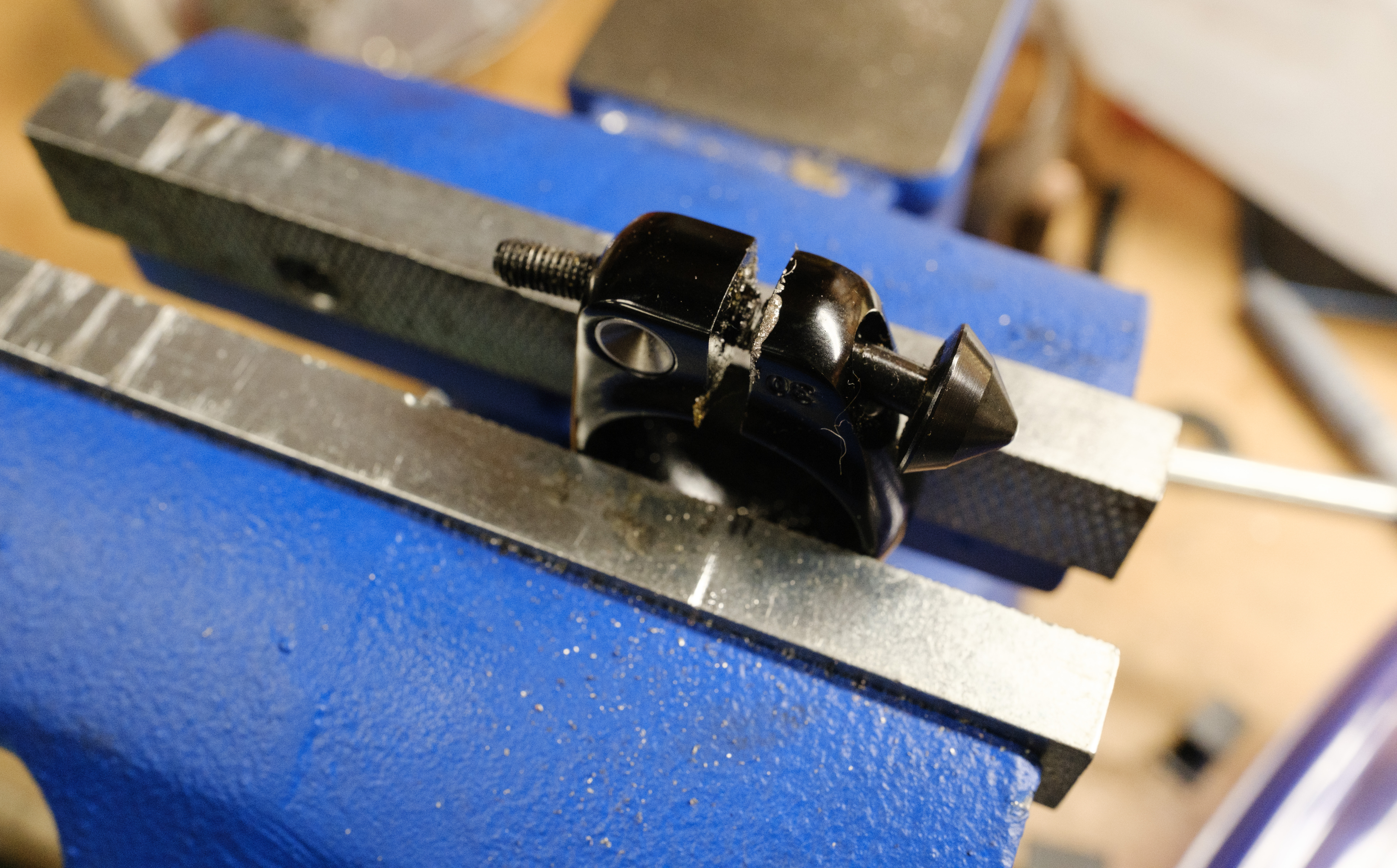 A seat collar in a bench vise with a cut locking skewer through it.