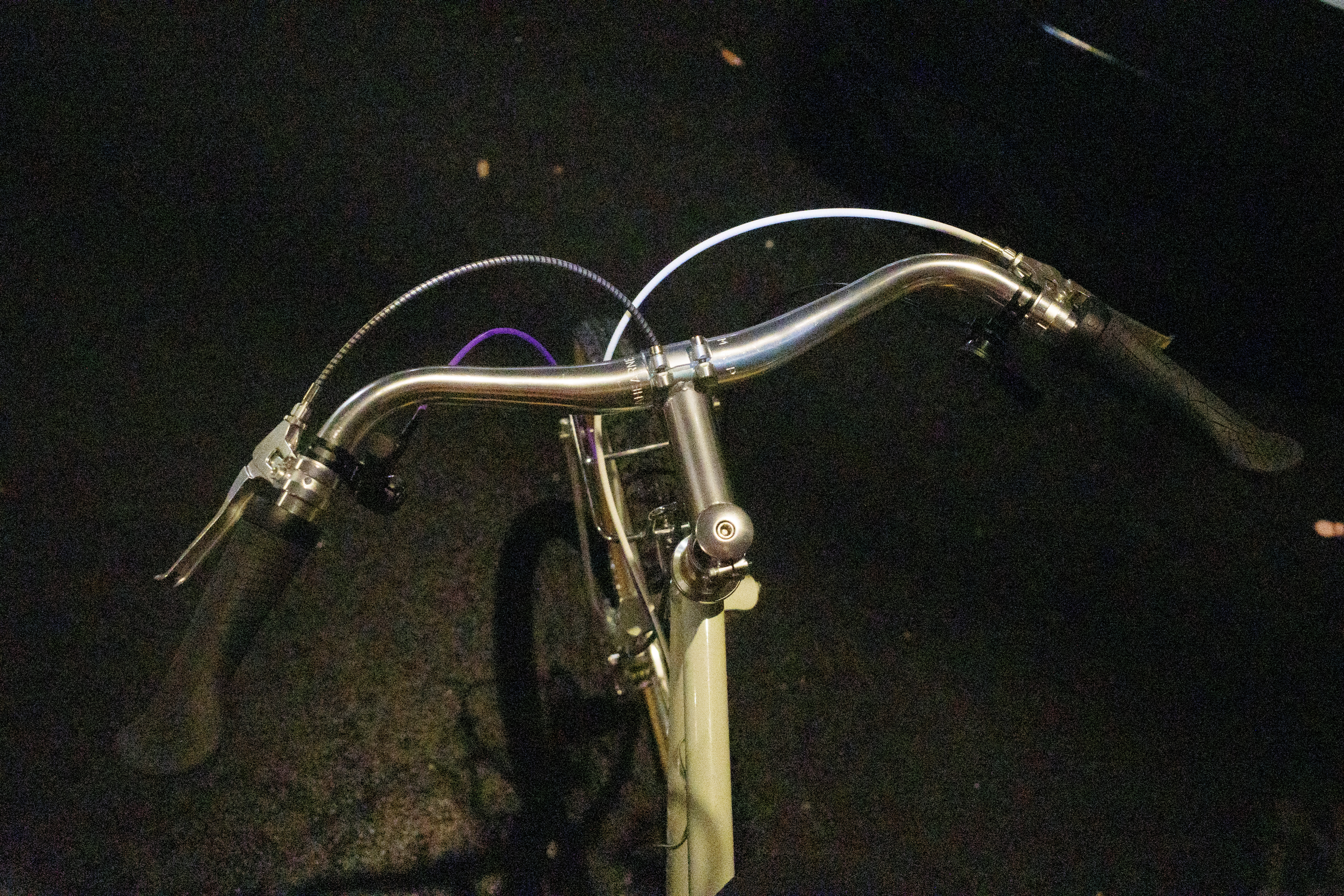 Looking down at the bike cockpit: silver stem, silver bars, silver Velo Orange brake levers, and black grips.