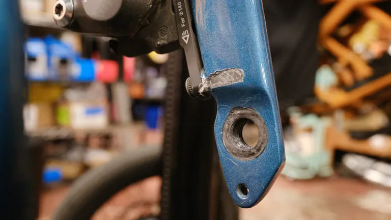 A close-up of the inner face of the non-drive side fork leg. There's a section where paint has been worn away and shows scraped-up carbon layup underneath.