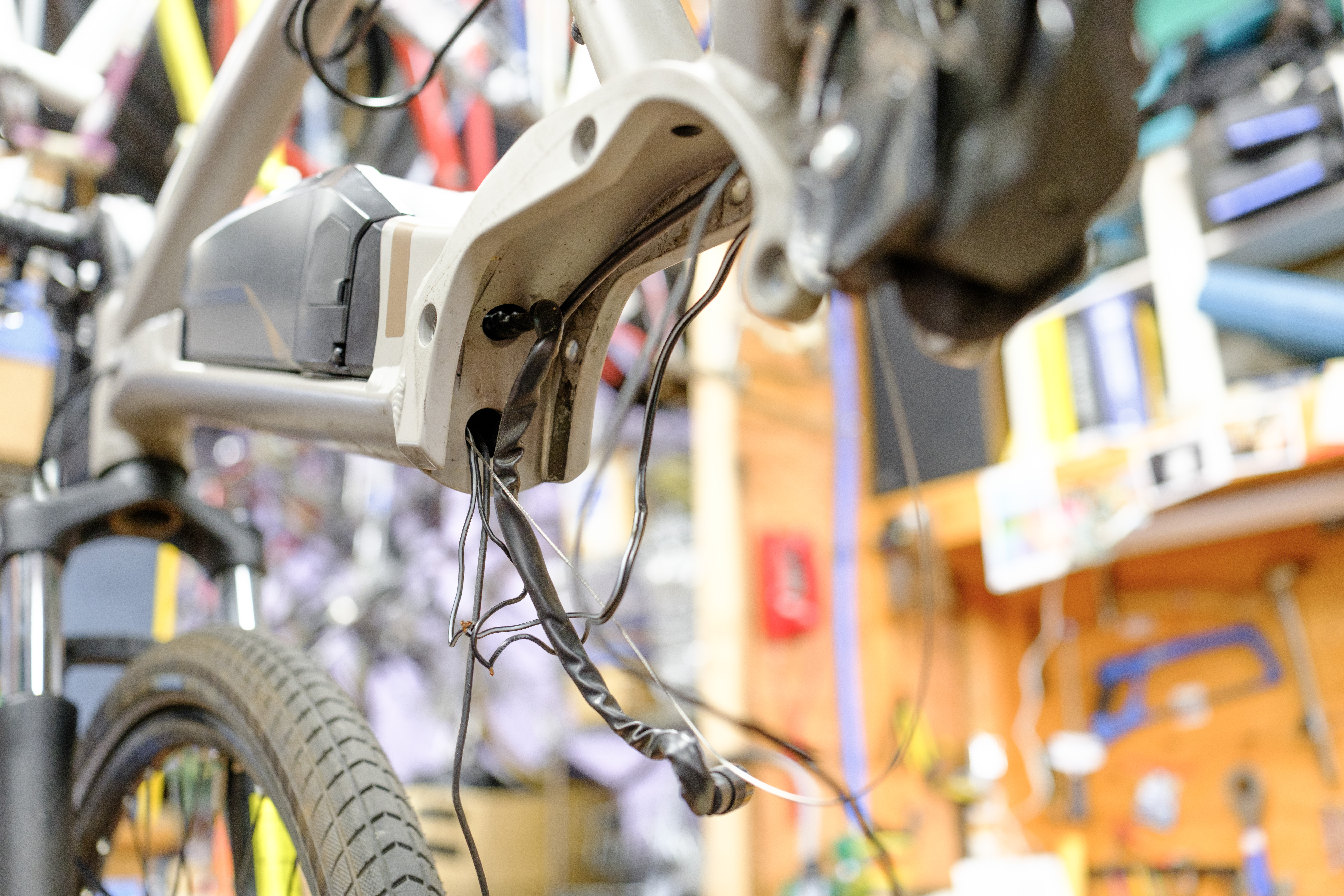 The motor cabinet of a mid-drive e-bike with various loose cables coming from the downtube and chainstay