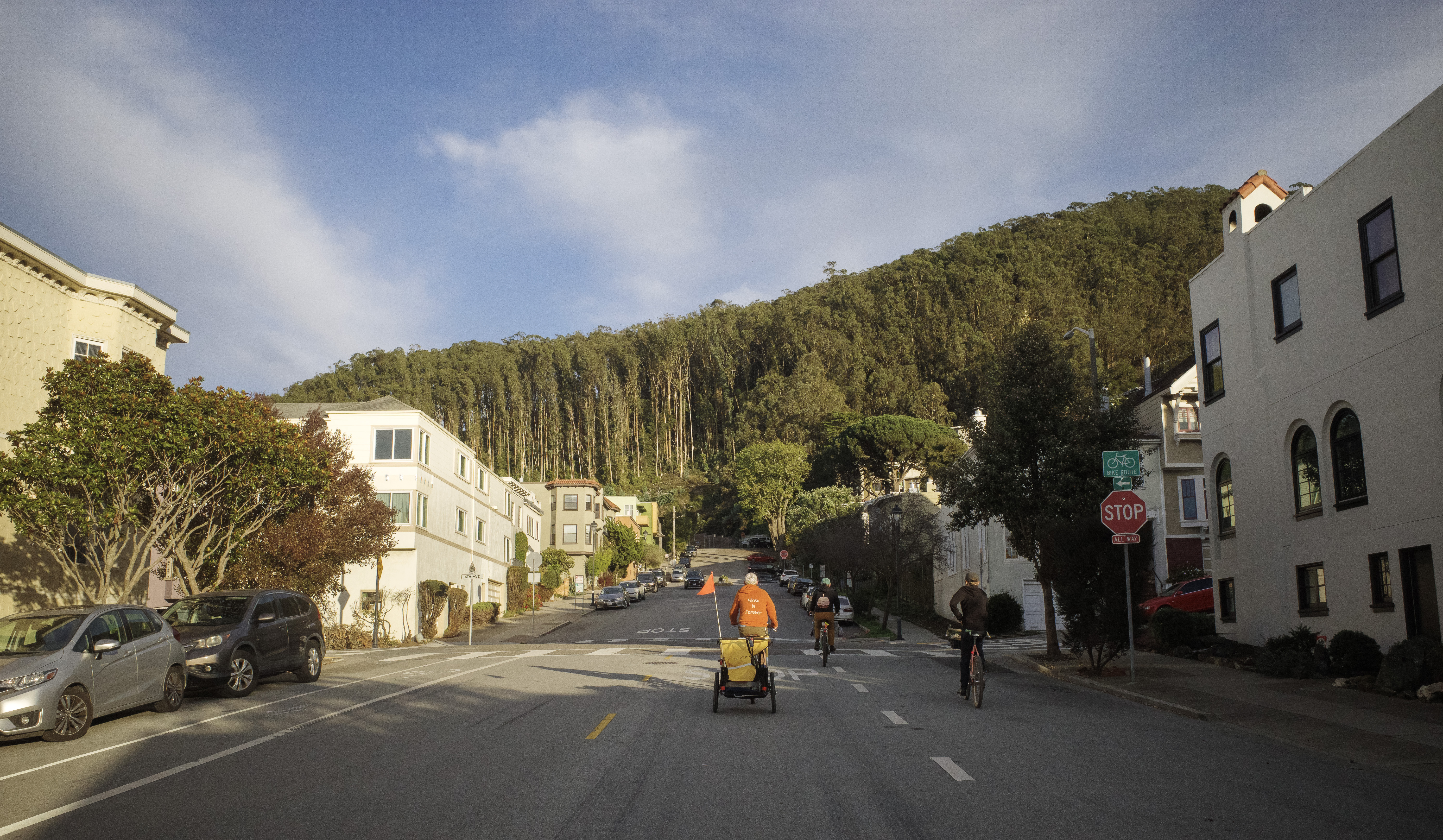 Jerry, Ben, and Sarah riding up Kirkham in some moody weather. A dark blue sky with white clouds hanging over the tree line.