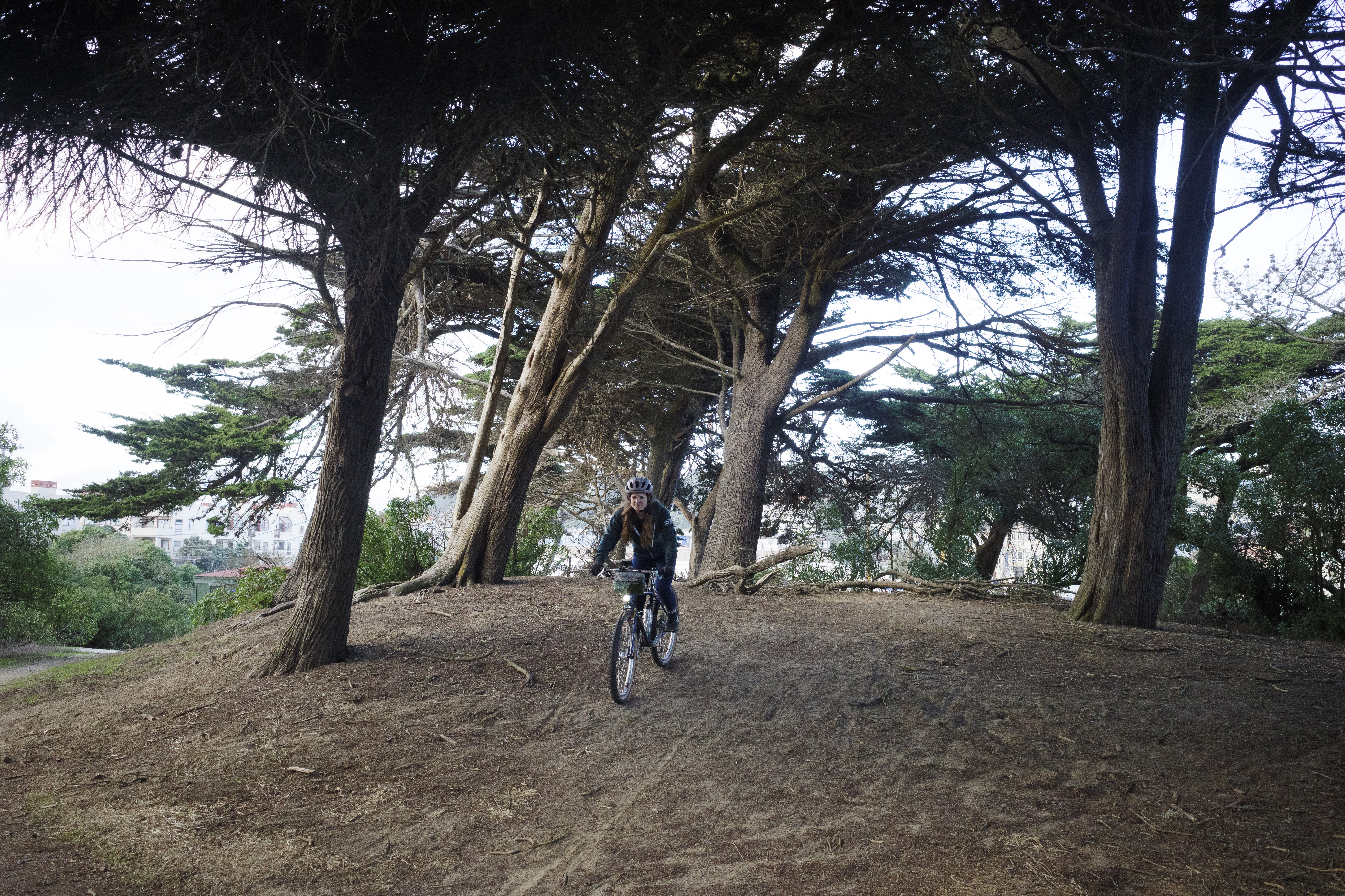 Kat biking down a sandy hill in front of a few trails