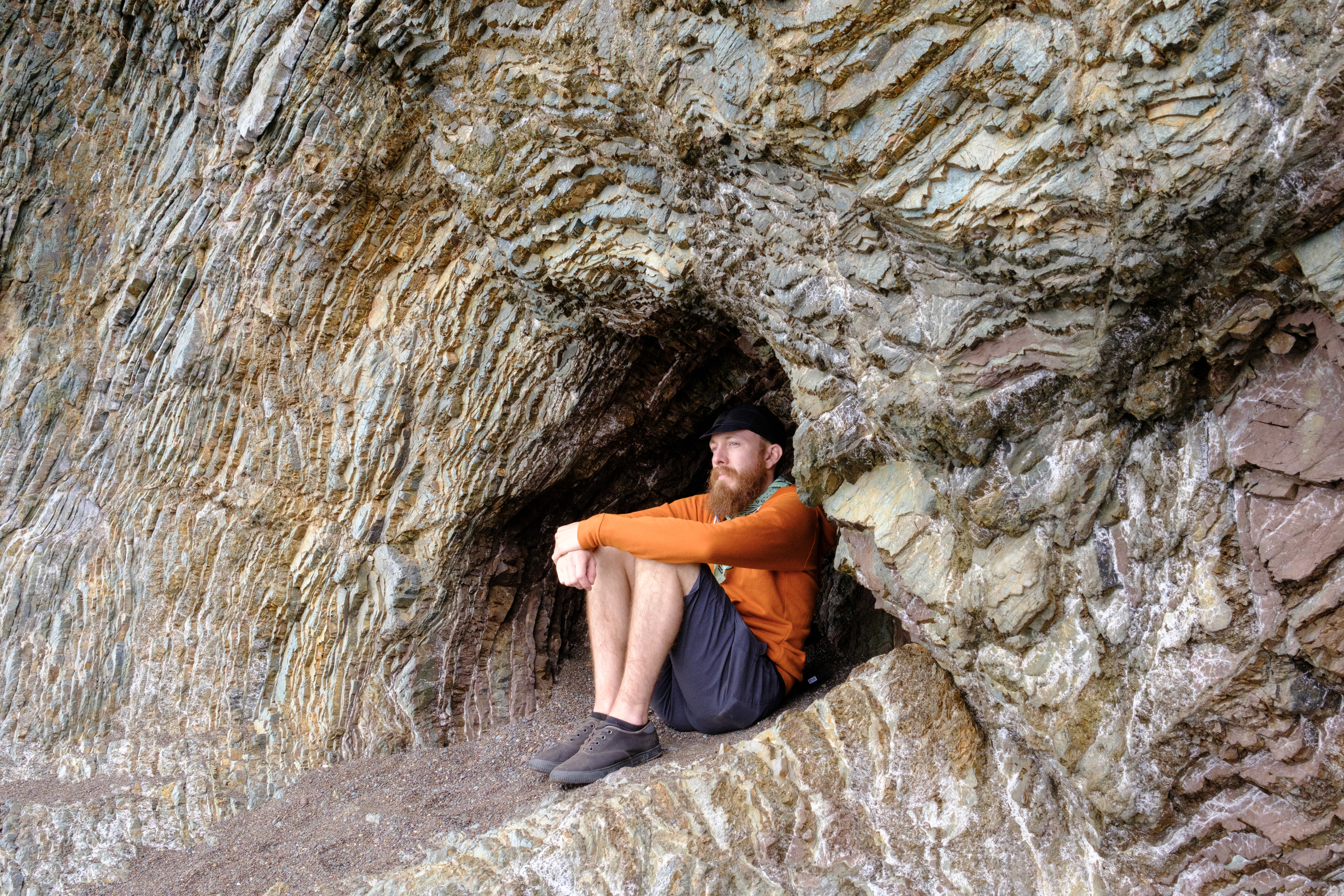 Ben sitting in a gap in jagged rocks which outlines his silhouette