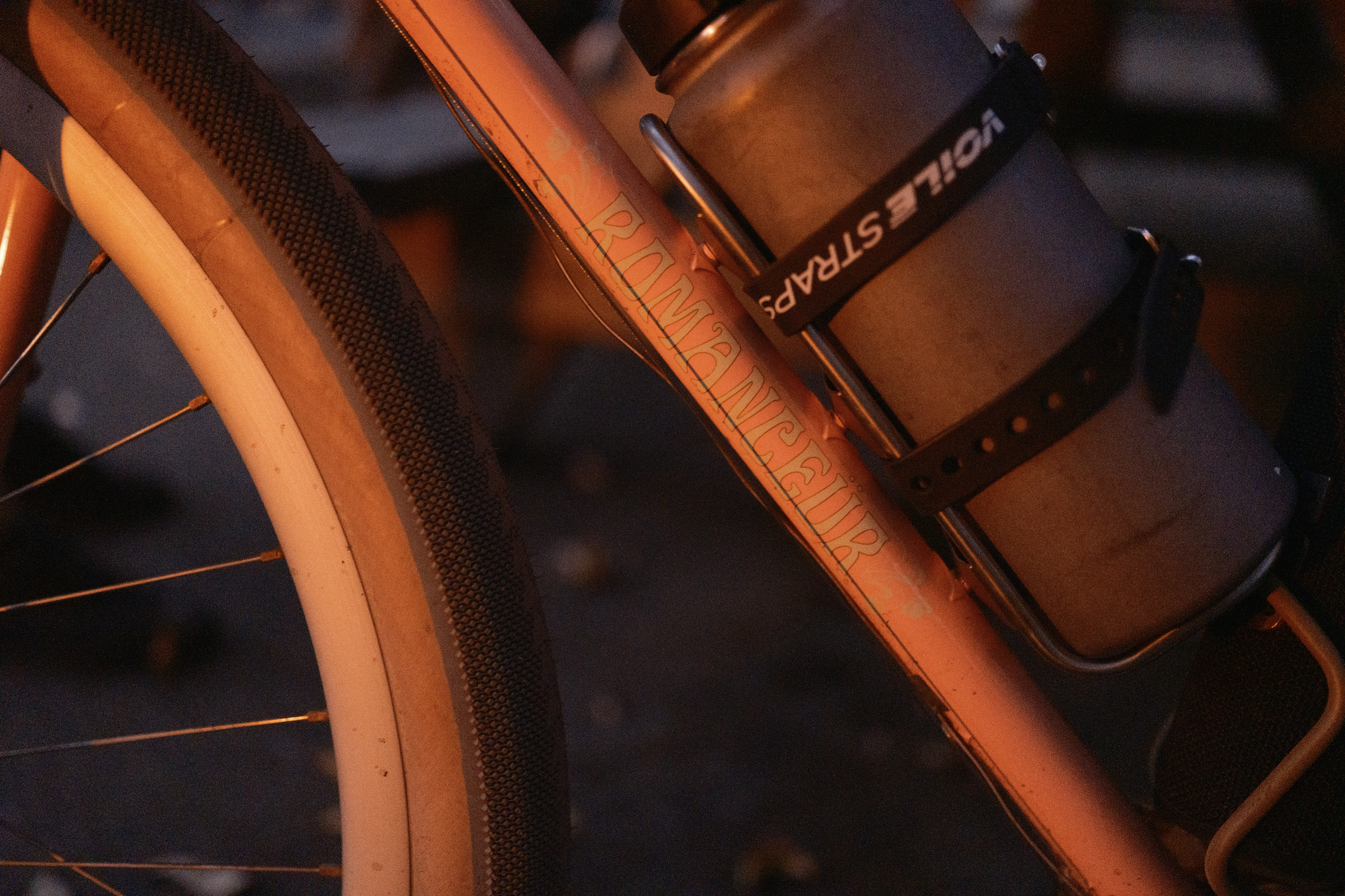 The Romanceur logo on the downtube of a bike in the glow of a campfire