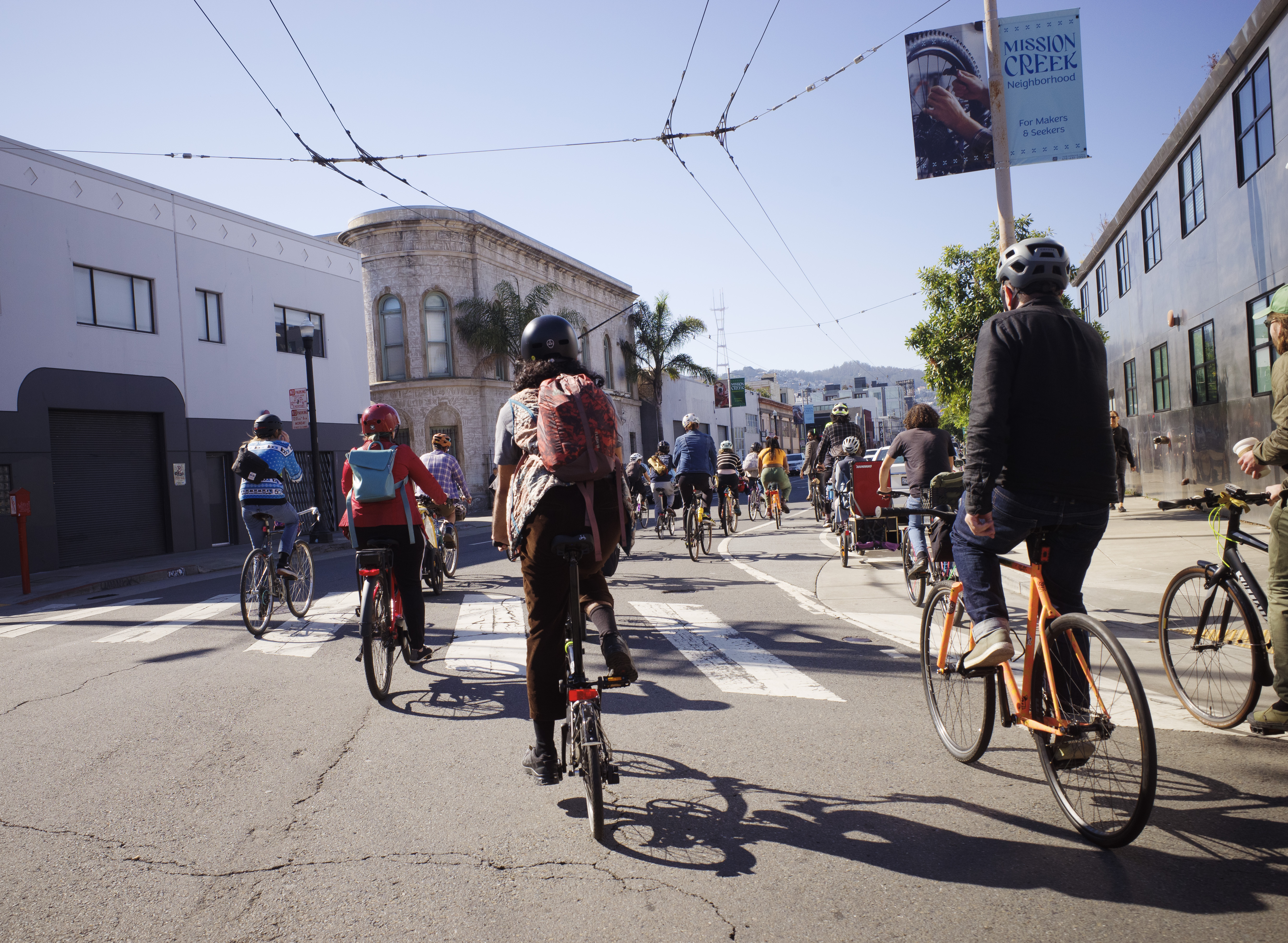 A large group of riders biking through an intersection in Mission Creek.
