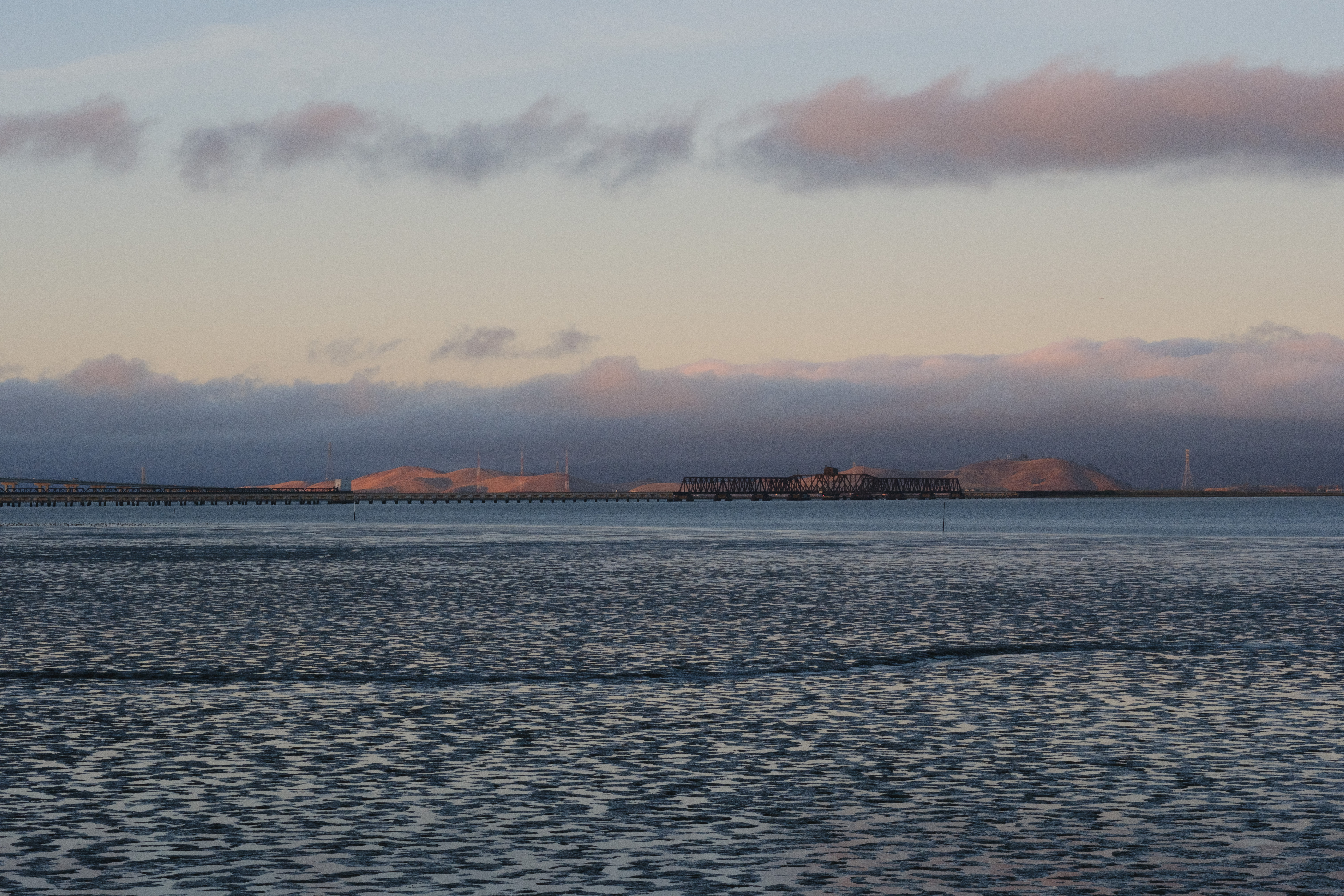 An unused bridge over the water with the evening fogline and golden hour colors