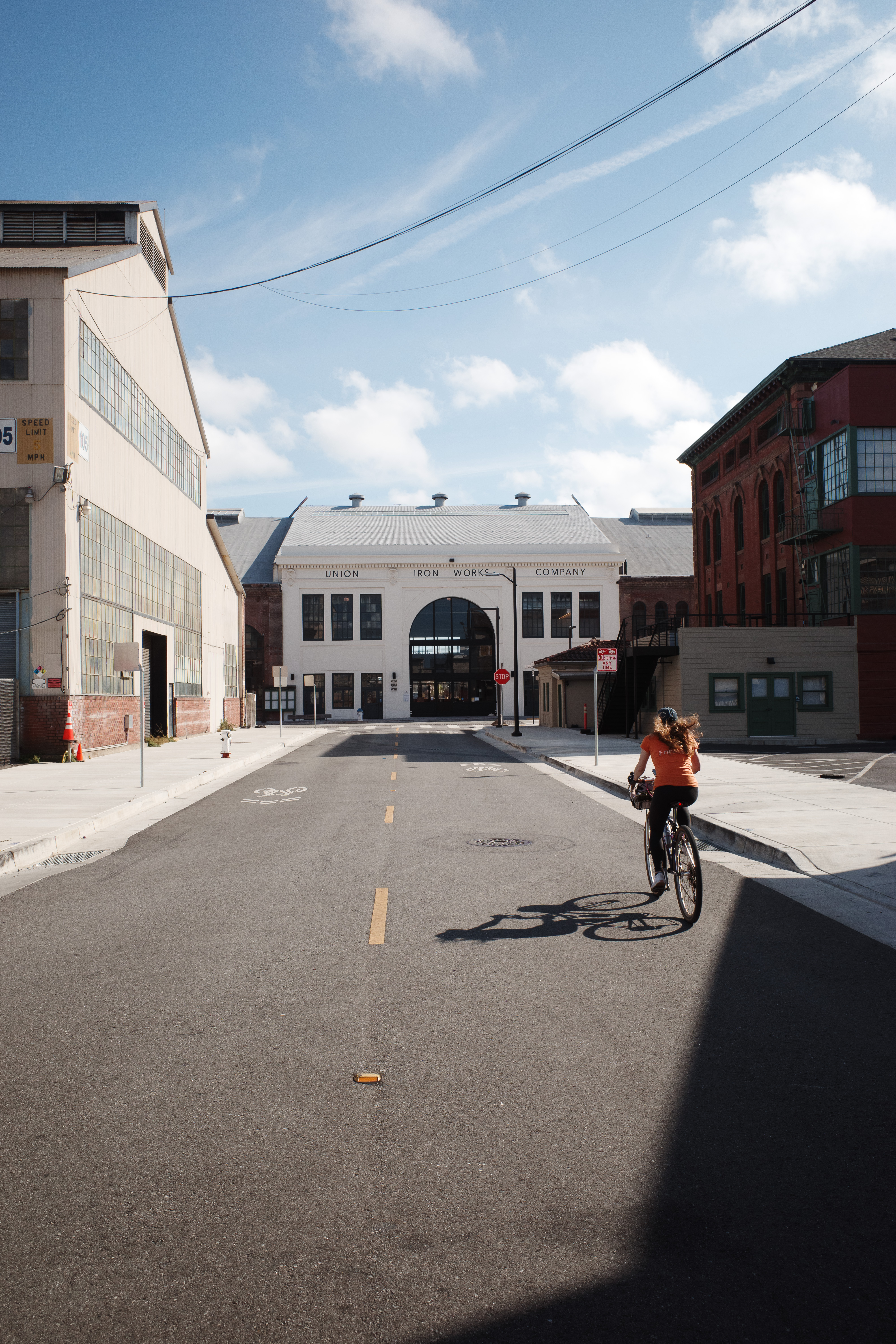 A woman riding on an empty road towards a stark  building labelled 'Union Iron Works Company'