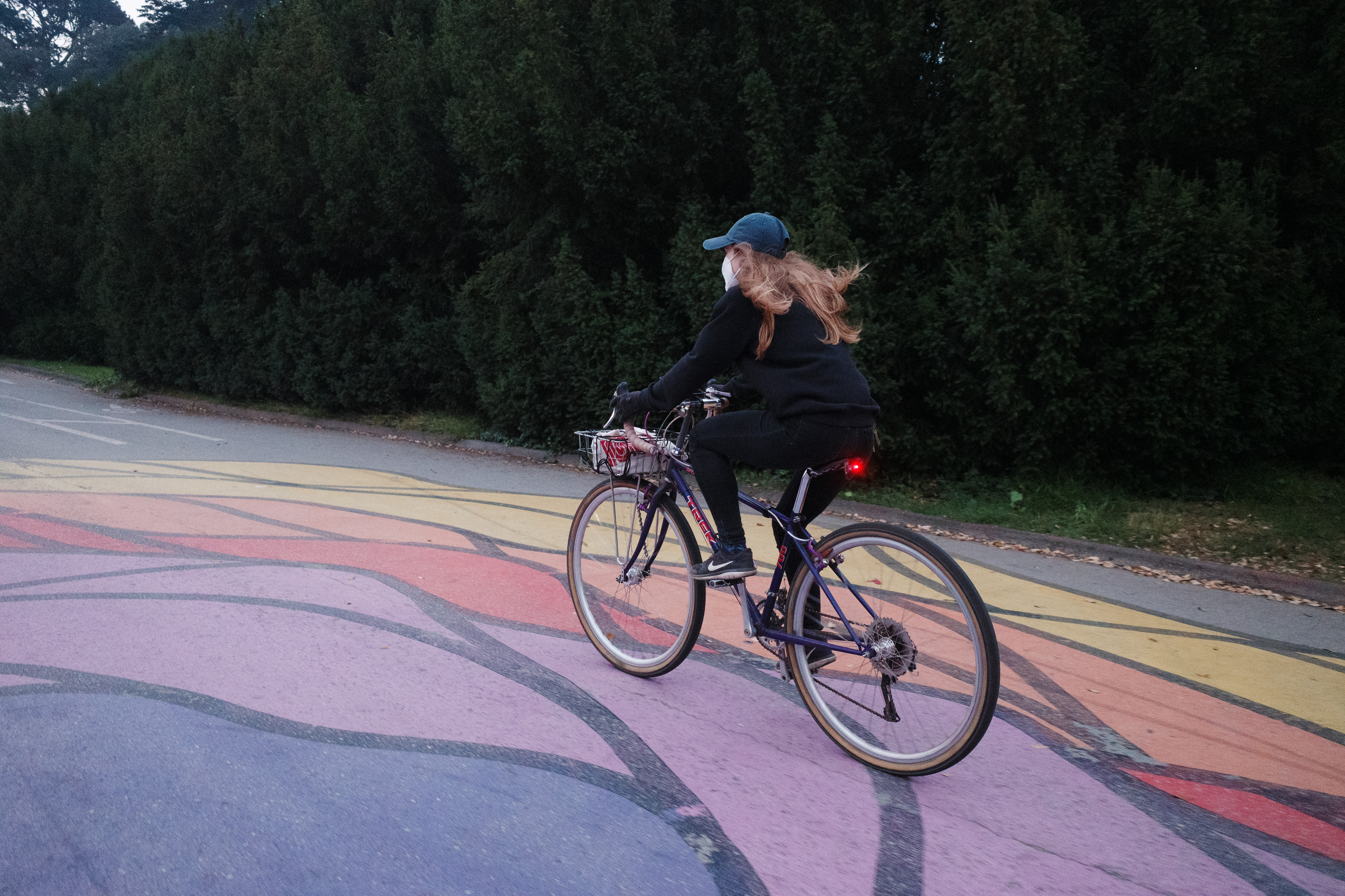 A woman riding a purple vintage Trek rigid mountain bike over a colorful mural