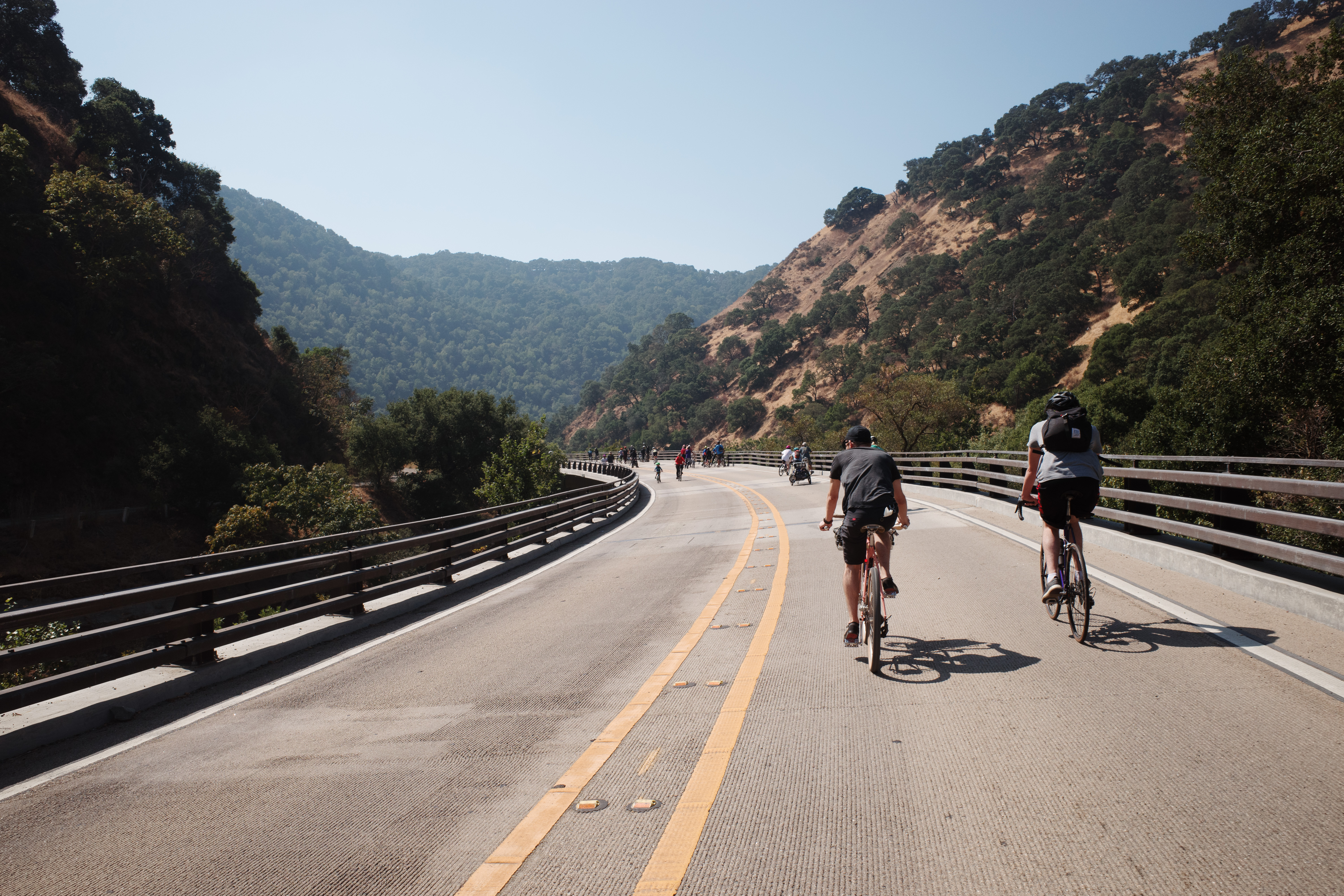 Multiple bike riders going through the banked turn of a highway without cars