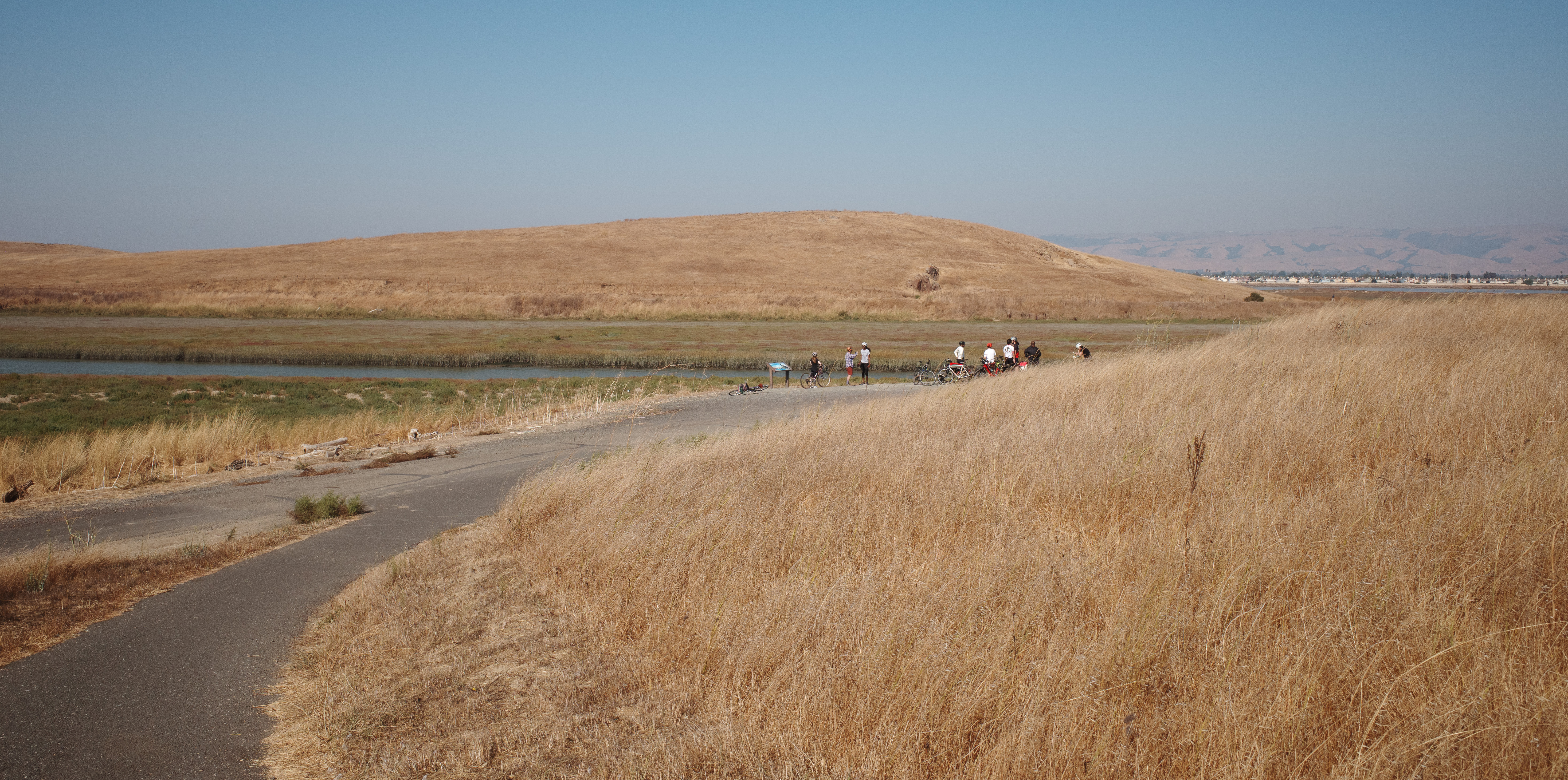 Serpentine hills in the foreground and midground with distant friends on bikes