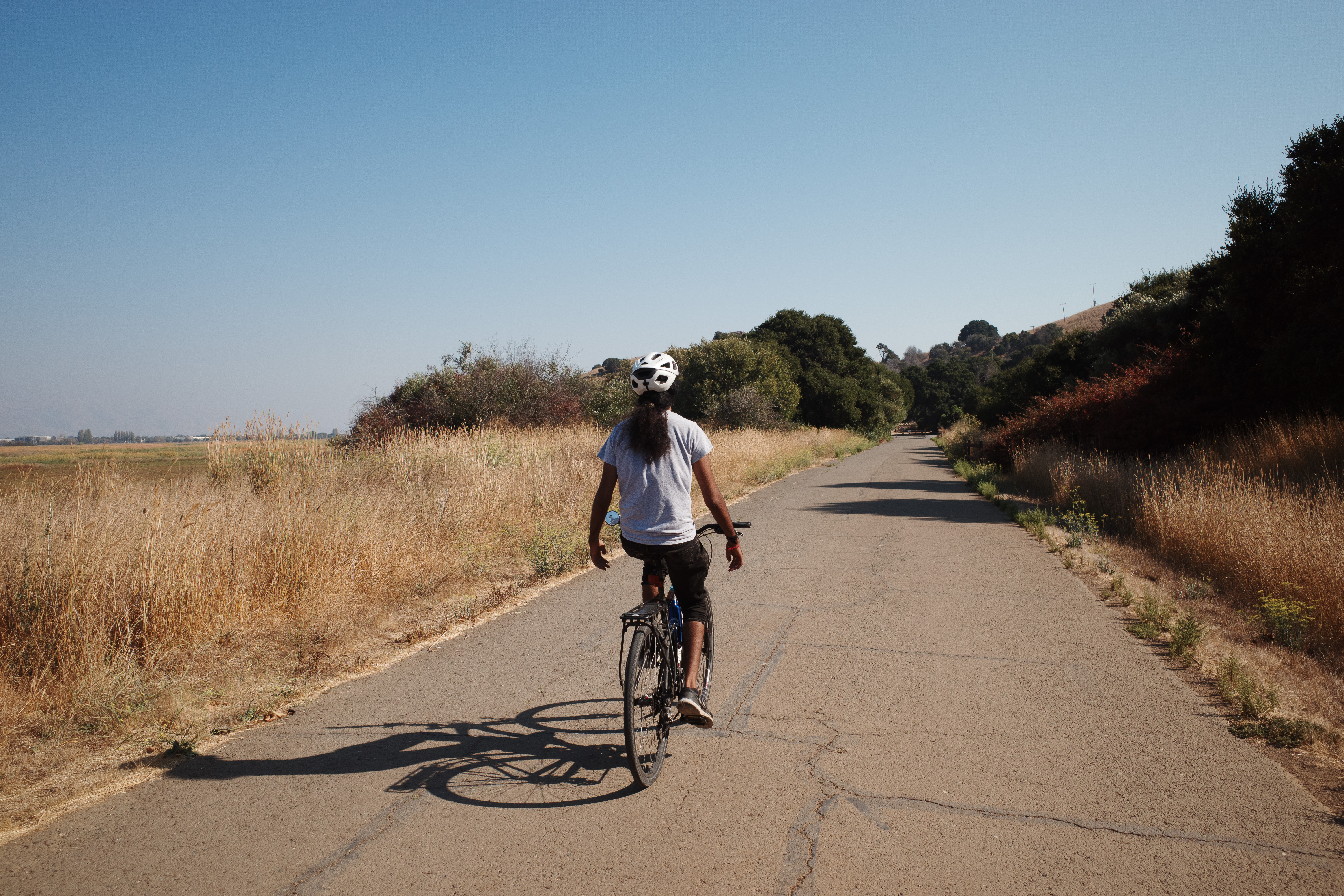 A rider biking without hands on the bars through a paved path