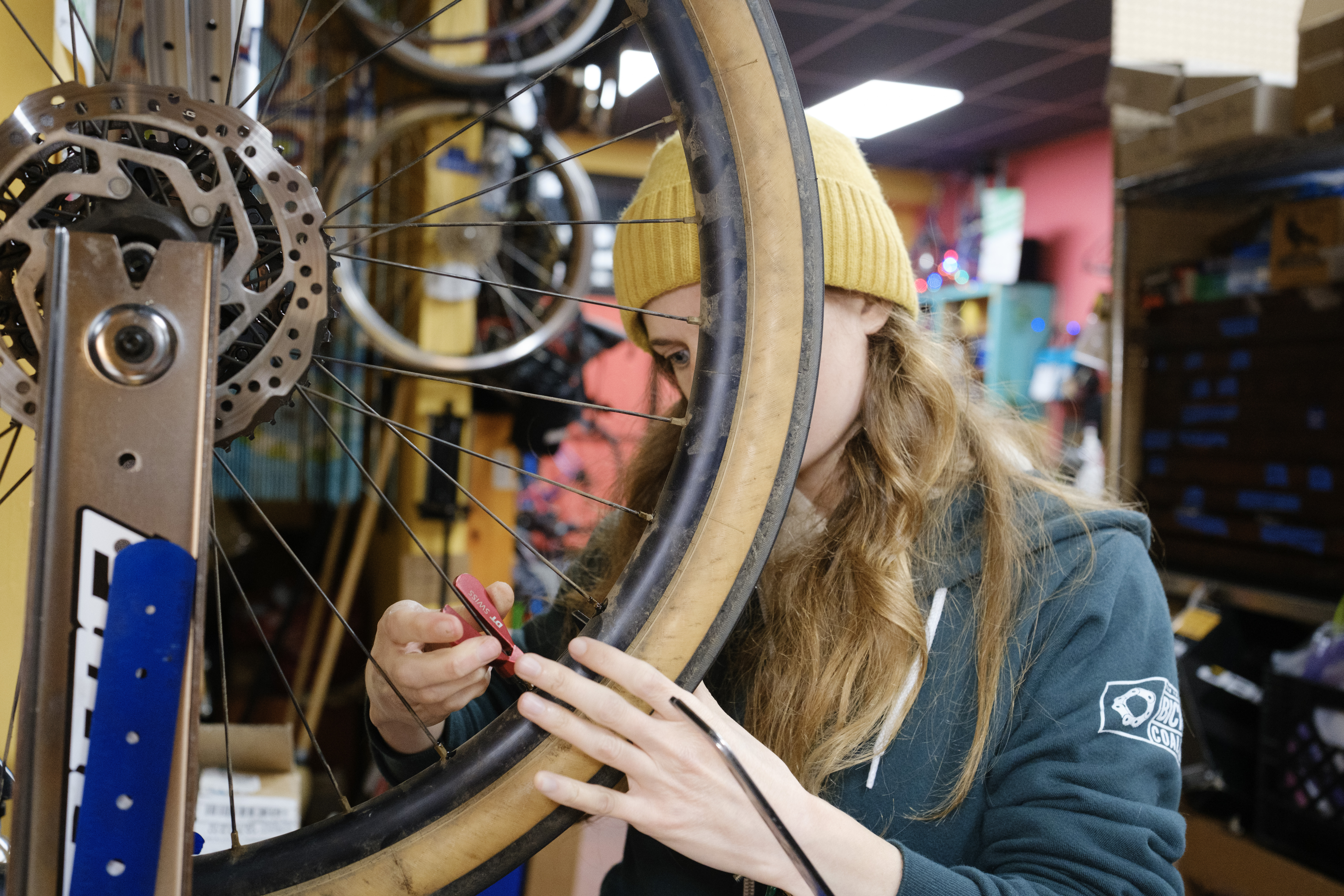 Kat behind the wheel with a spoke wrench in her hand adjusting one spoke nipple