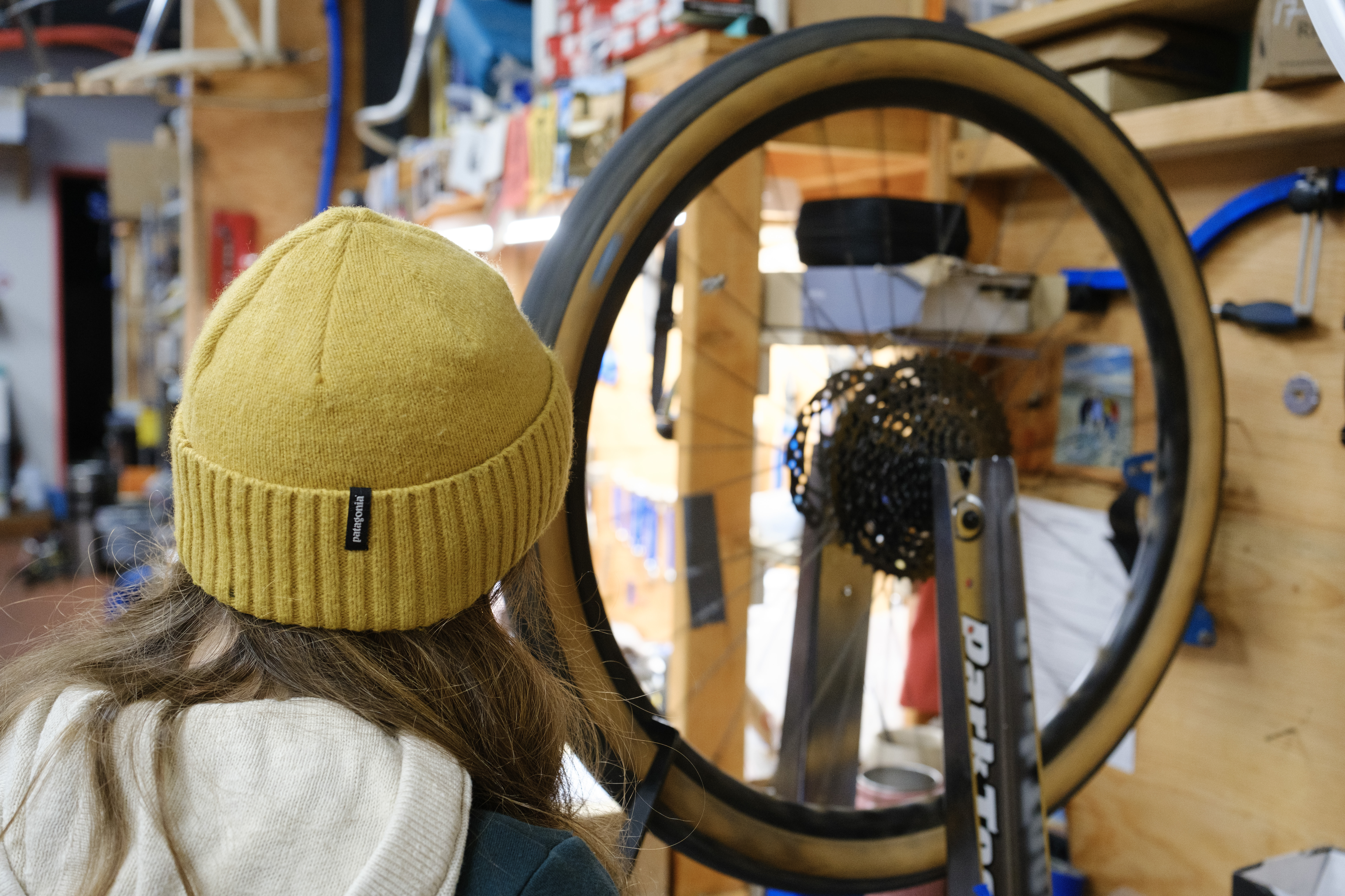 The back of Kat standing in front of the wheel assessing its trueness with the gauge